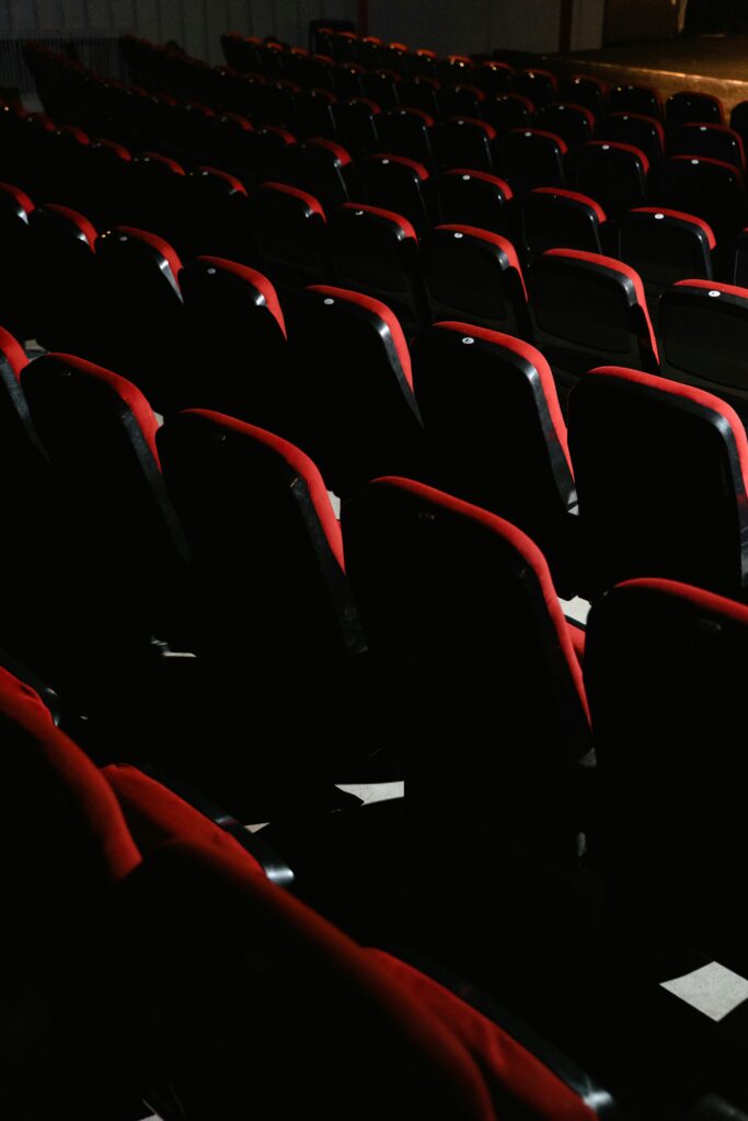 An empty theater with red seats, dim lighting captures a tranquil ambiance.